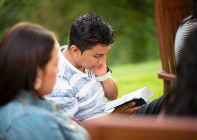 boy in blue stripped shirt reading book of mormon
